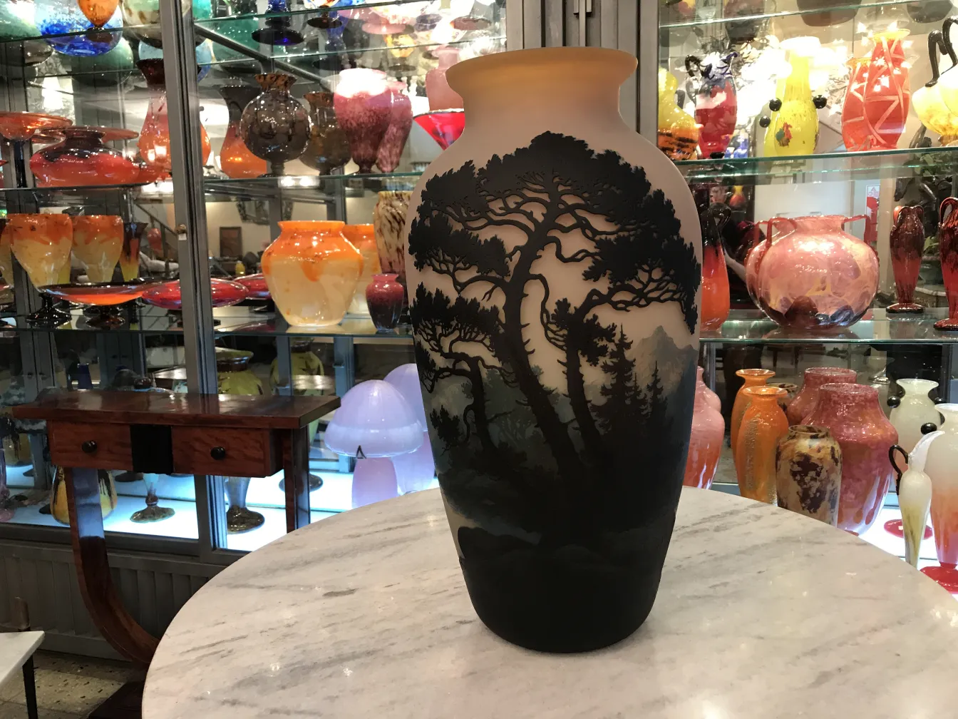 Vetro firmato Muller Fres con design antico e paesaggistico, circondato da vari oggetti decorativi.