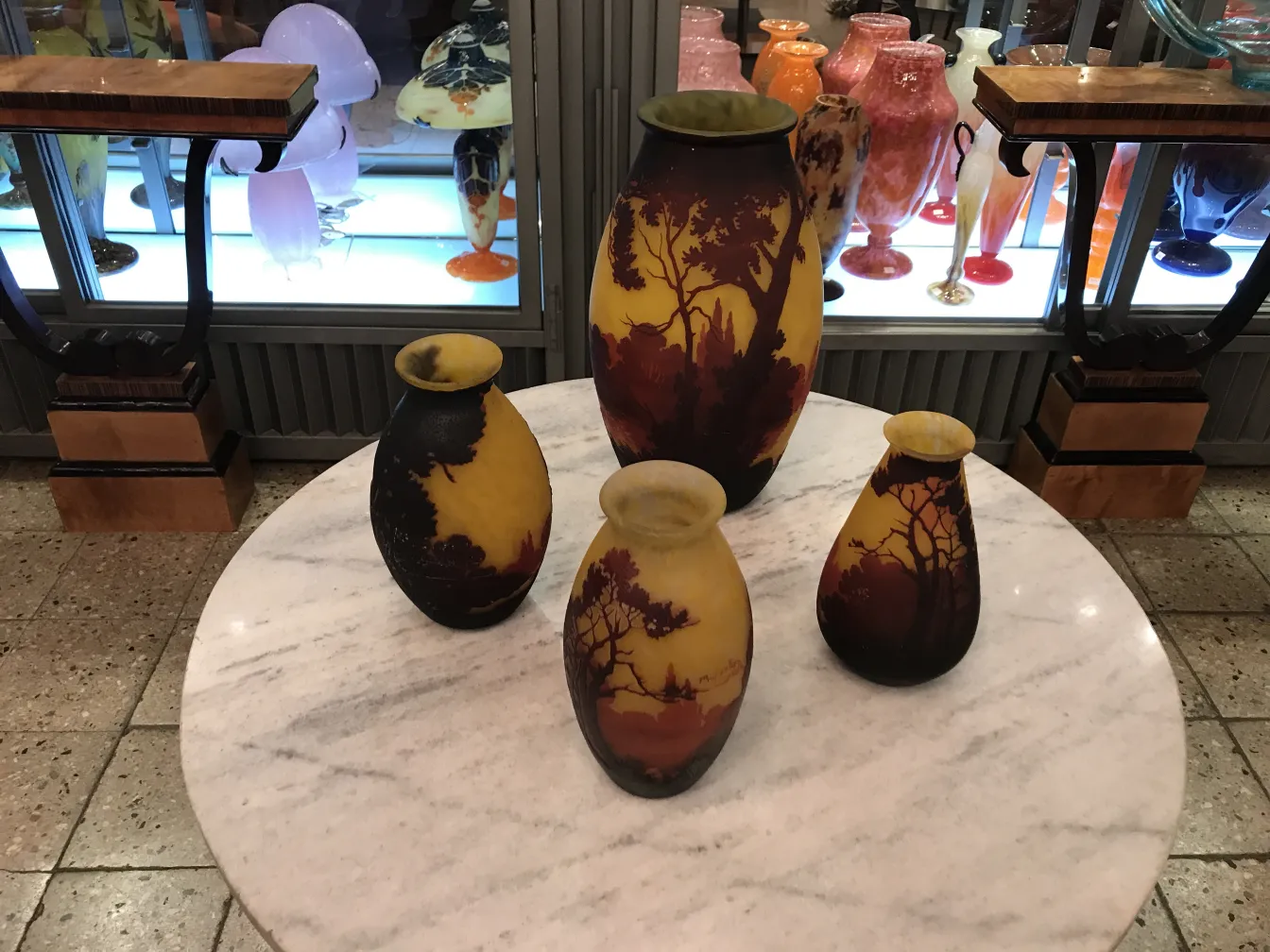 Antique glass vases, some with tree silhouettes, on display.