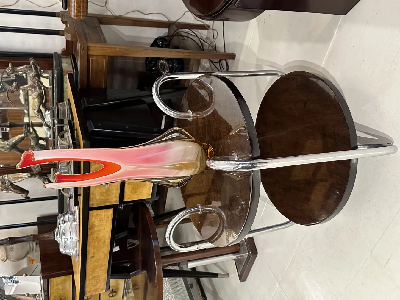 Murano vase in pink tones and stylized shape, surrounded by antiques.