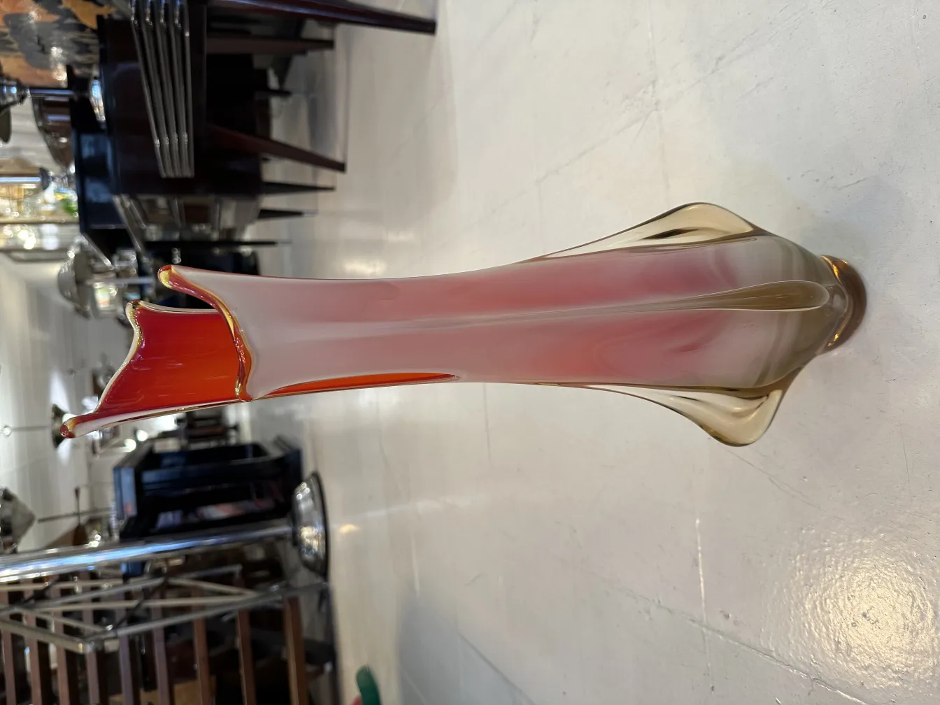 vaso de murano com tons vermelhos e dourados, design elegante com bordas onduladas, ambientado em espaço clássico