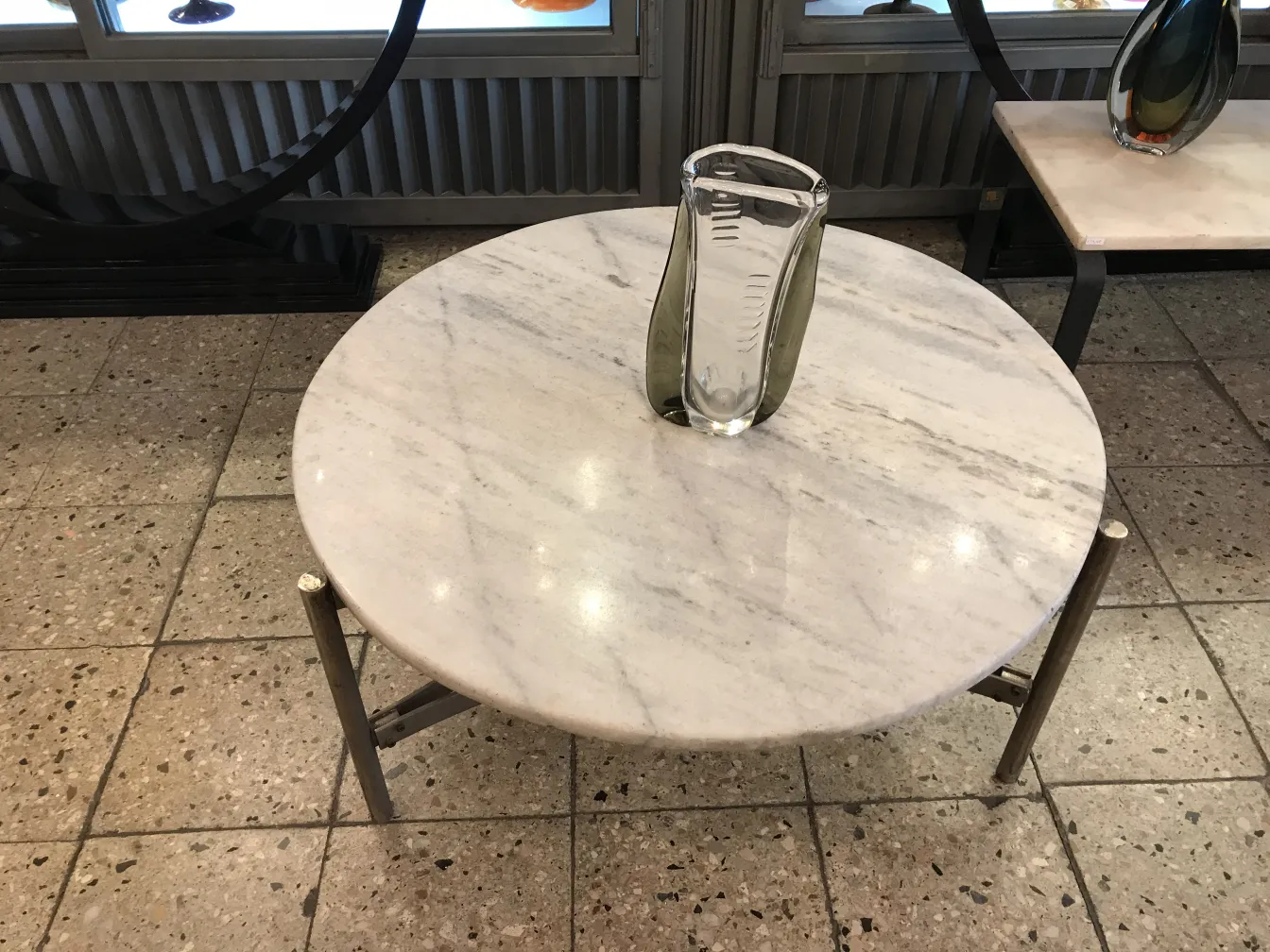 vaso di murano su un tavolo bianco, circondato da antichità