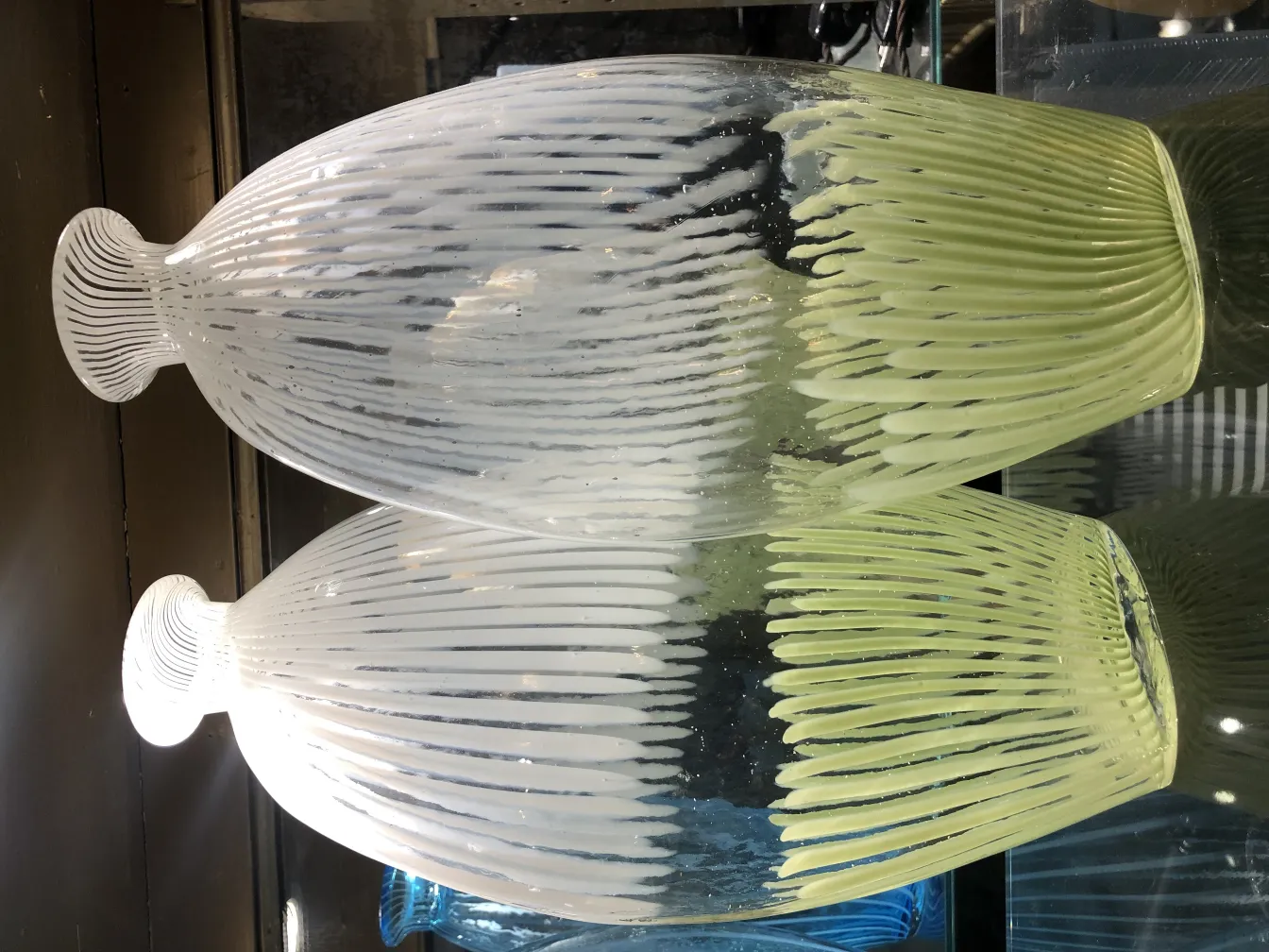 vaso de murano antigo, design de linhas suaves e onduladas, cor verde e branco, em um ambiente elegante