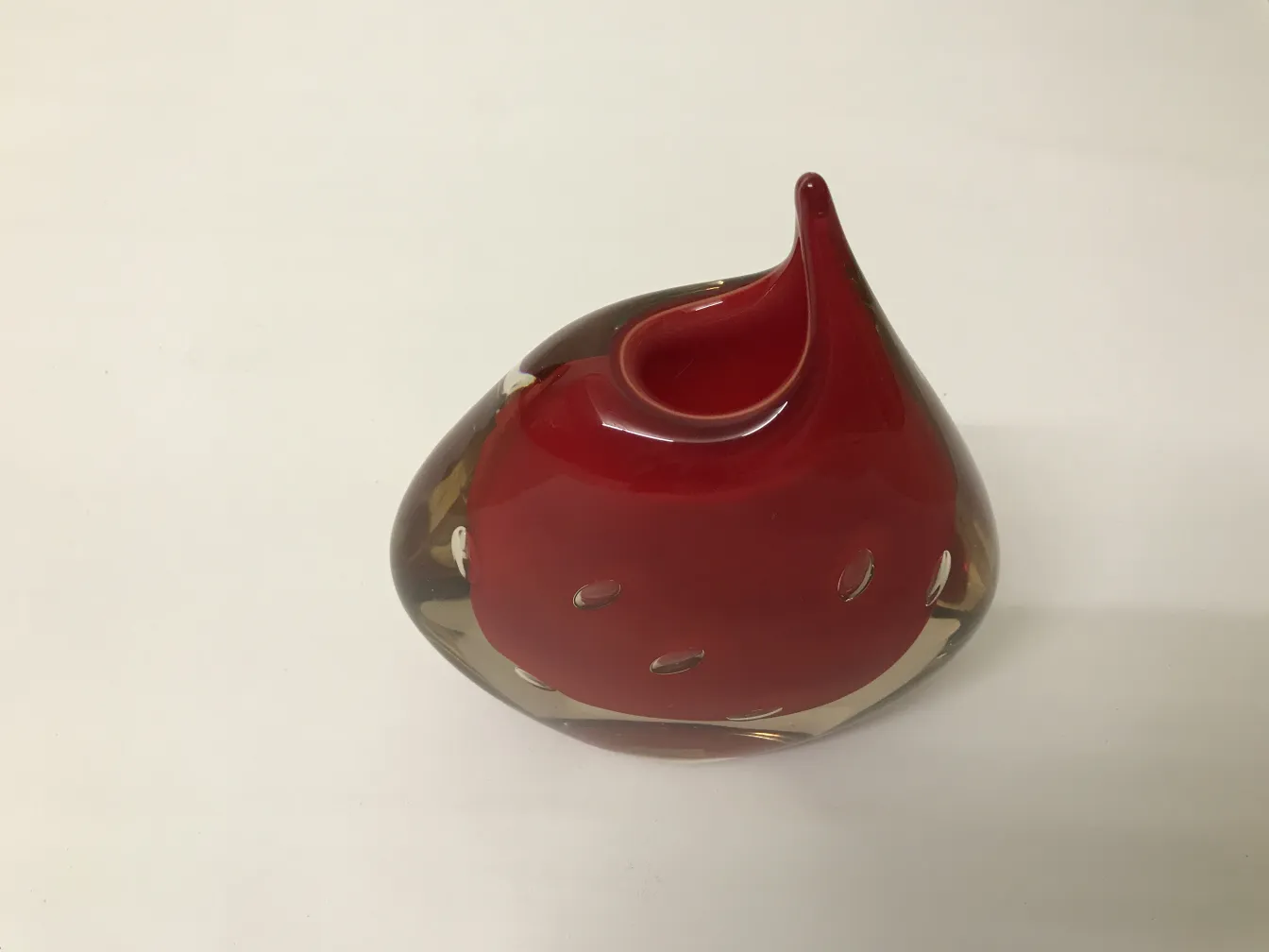 antique murano vase decorated with distinctive shape and shiny red color in a neutral setting.