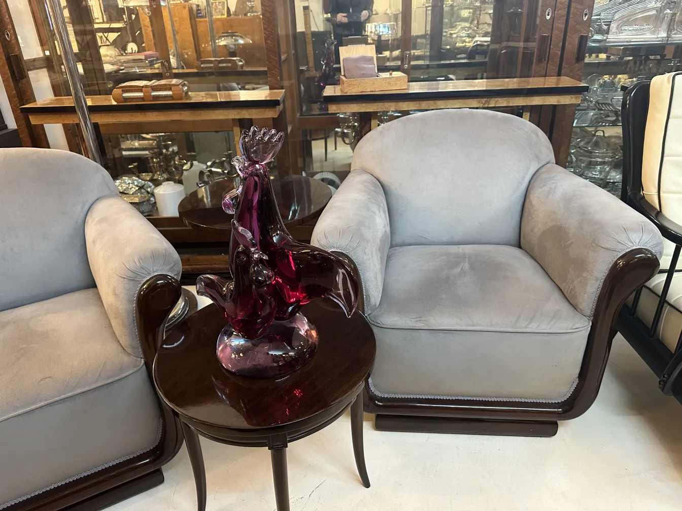 Scultura murano in tonalità viola su tavolino rotondo, in un ambiente vintage con poltrone