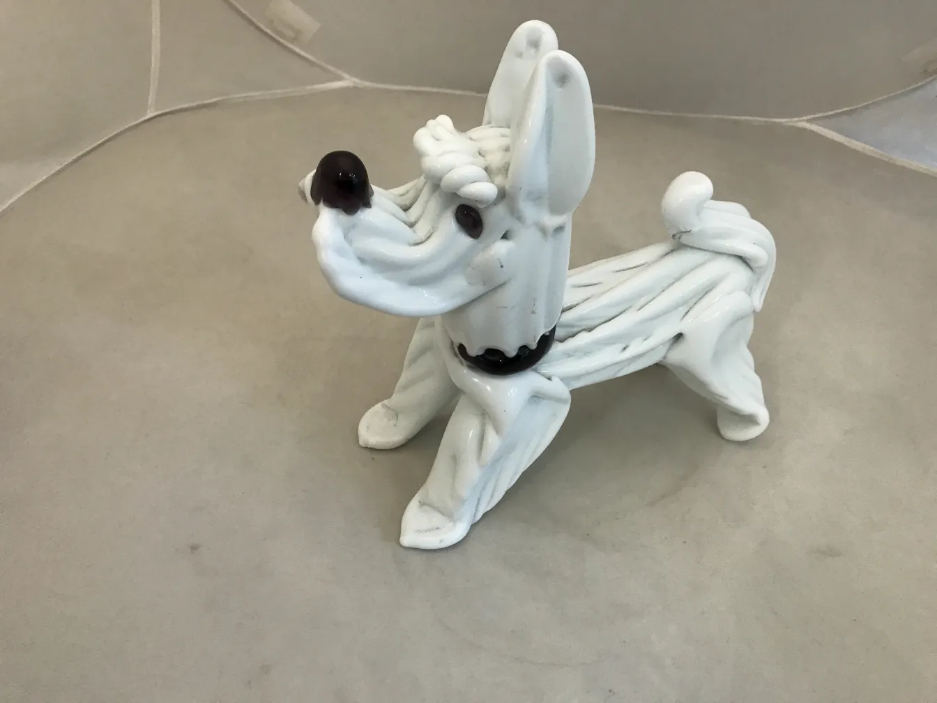 scultura murano di un cane bianco con dettagli scuri su sfondo neutro
