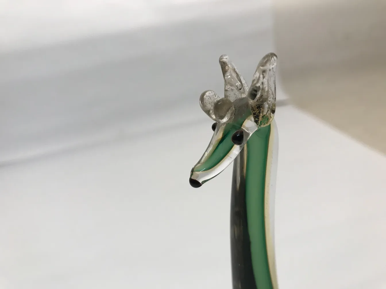 古老的穆拉诺动物雕塑，绿色调和黑色细节，突显在白色背景上。