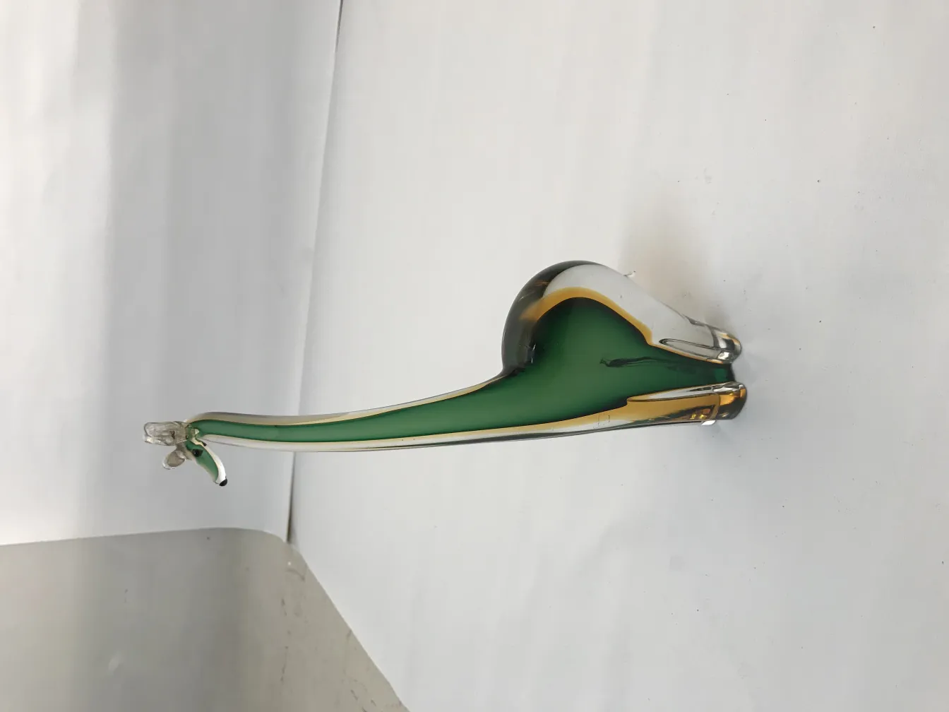 sculpture de murano aux tons verts et dorés, présentant des contours élégants. Fond neutre