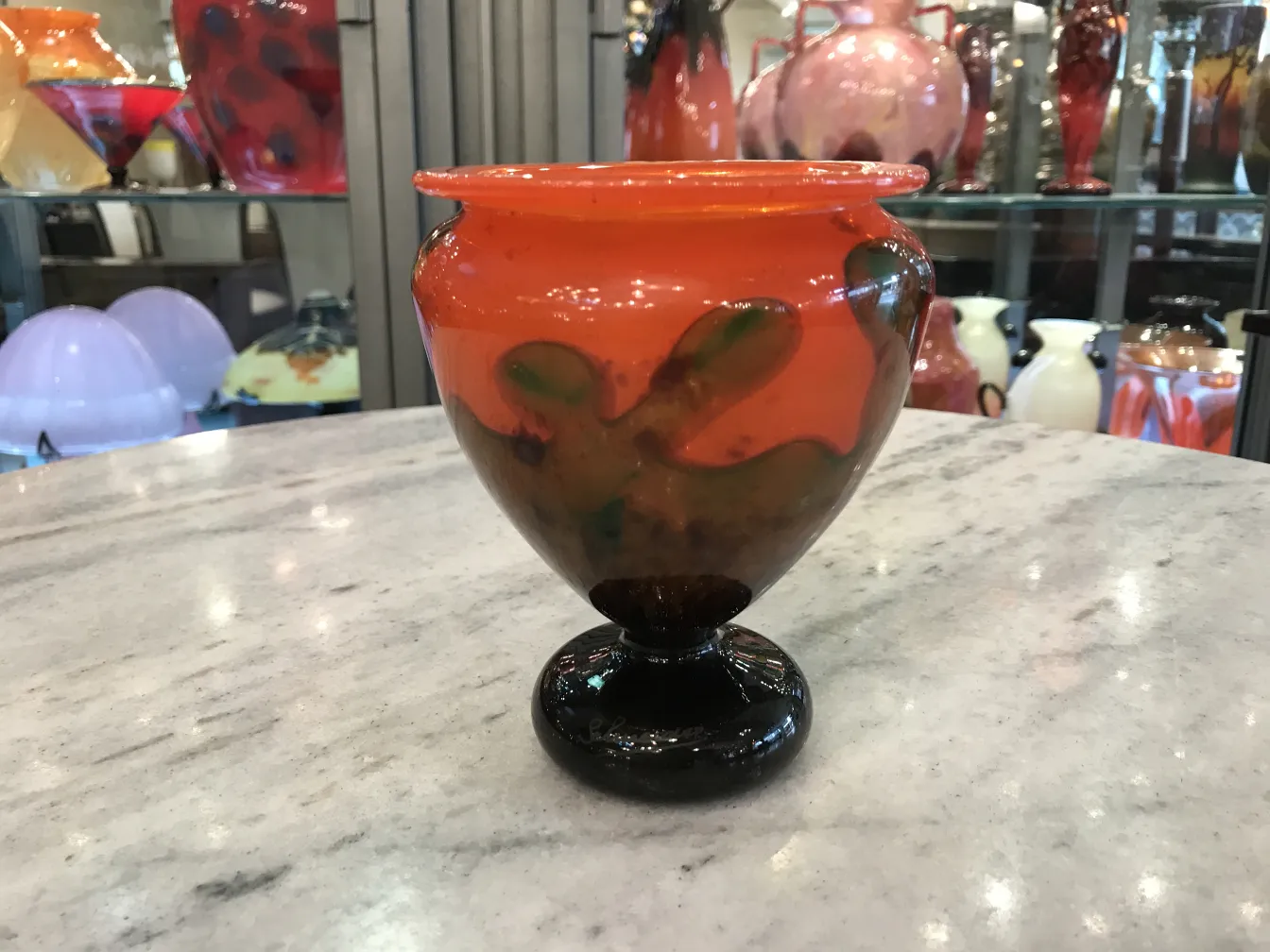 Verre signé Schneider aux couleurs vives avec une base sombre, décoratif sur fond varié.