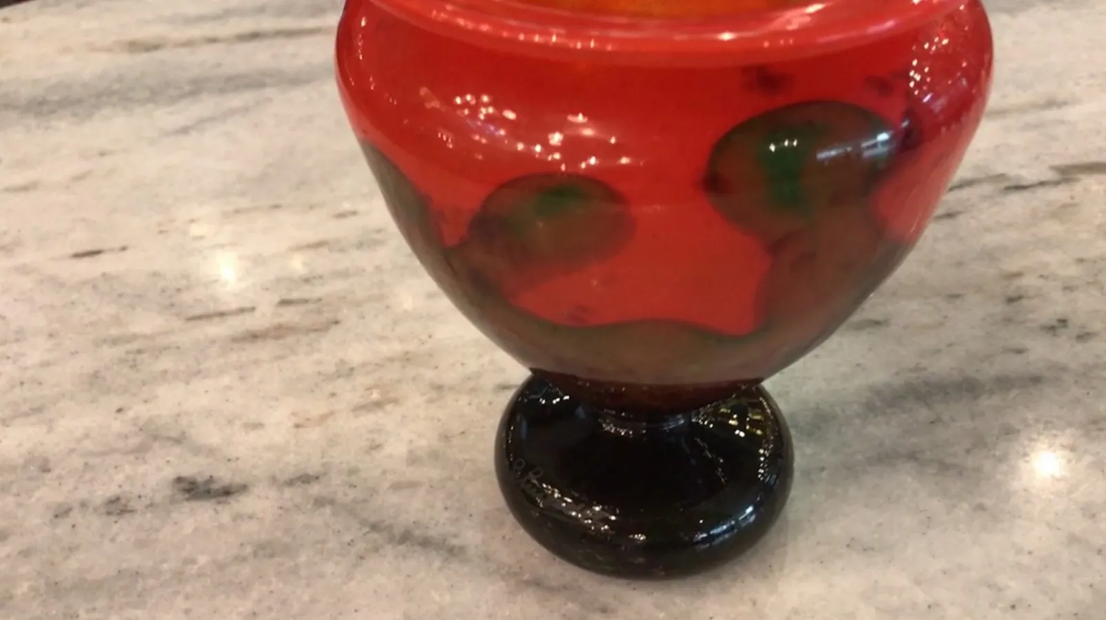 Colorful glass with a black base and visible signature.