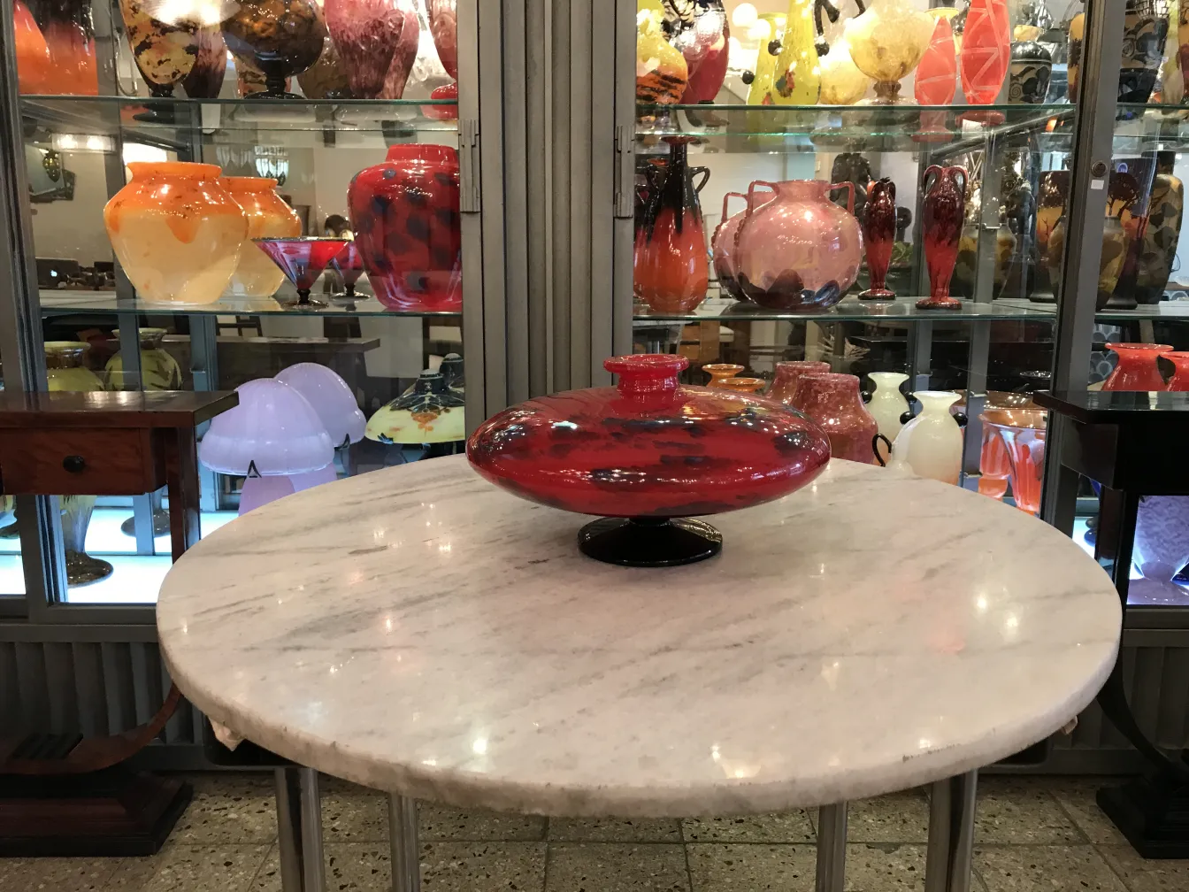 Vidrio firmado de Schneider con forma circular y base negra, antigüedad, en un entorno de antigüedades.