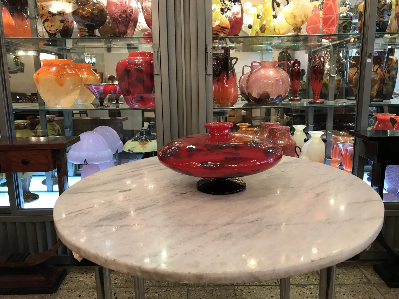 Antikes signiertes Glas von Schneider in strahlendem Rot, ausgestellt zwischen anderen Glasgegenständen.