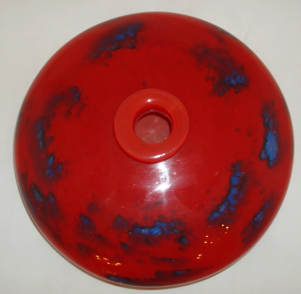 Vetro firmato Schneider rosso con dettagli blu in forma rotonda, esposto in un ambiente antico.