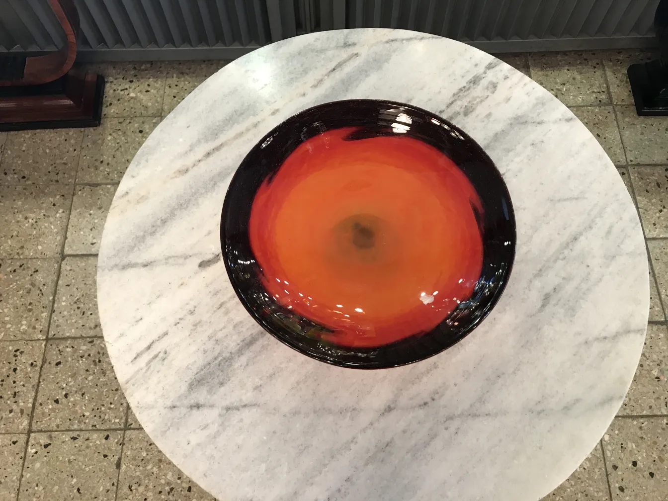 decorative bowl with orange and black design on a marble table