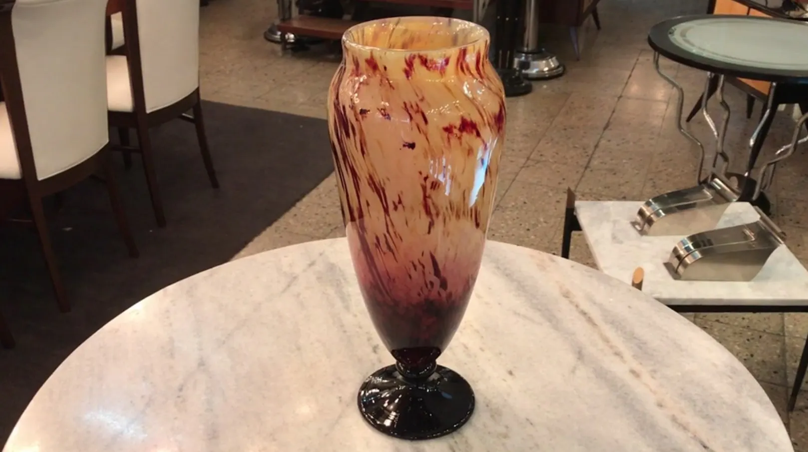 Vase de vidrio firmado Schneider, con un diseño decorativo en tonos ocres y rojizos, en un entorno elegante.