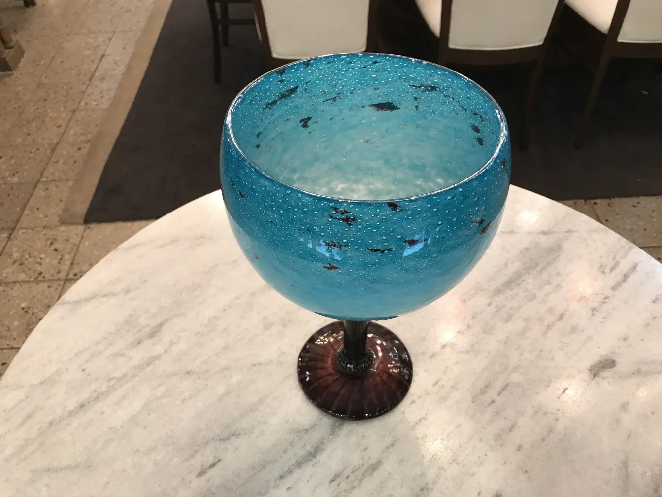 Blue signed glass with dark base on marble table.