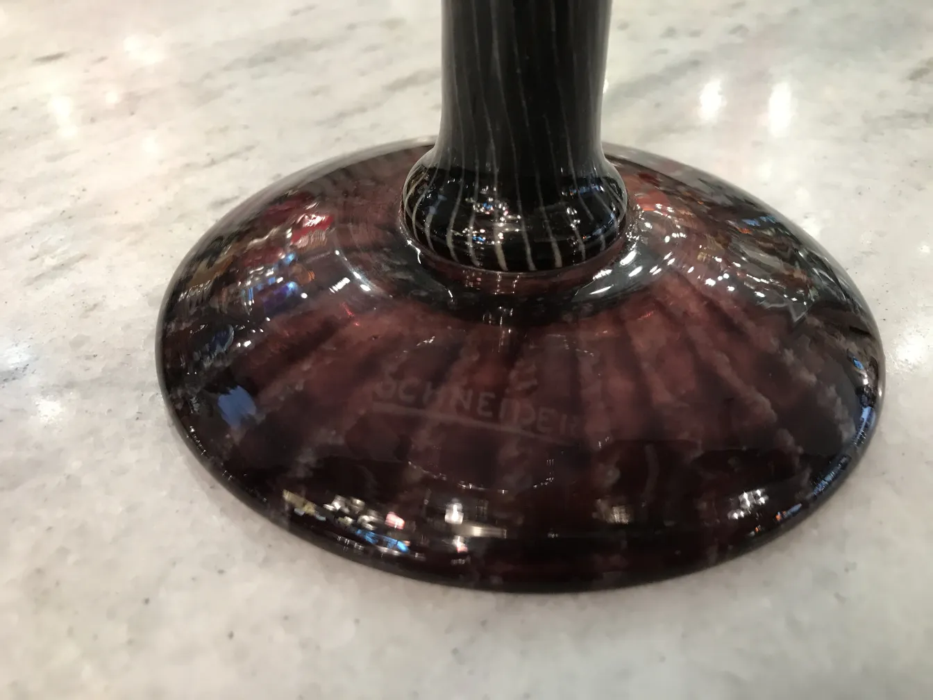 Base de vidro com assinatura visível de Schneider em um ambiente antigo.