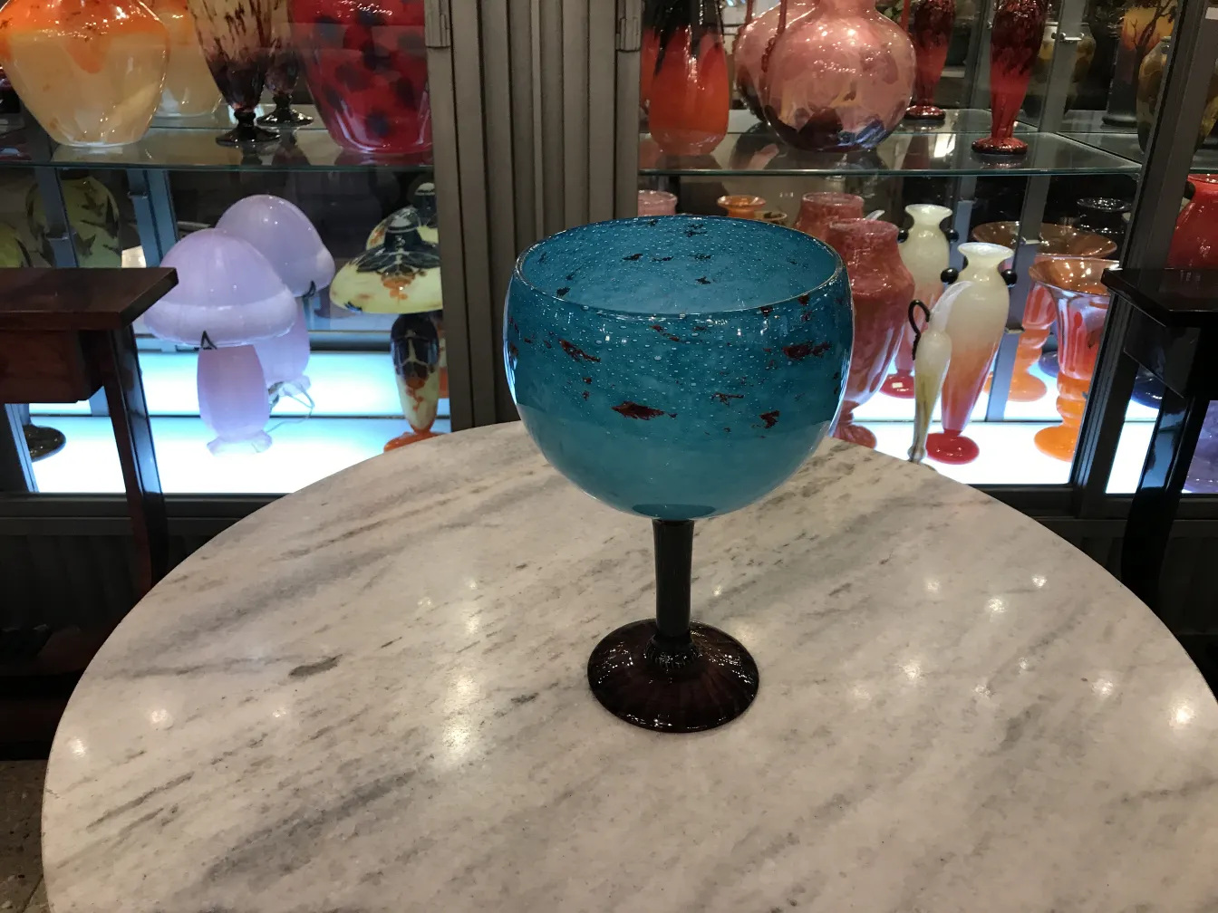 Vetro antico firmato da Schneider, colore blu brillante su tavolo in marmo, sfondo con varie antichità.