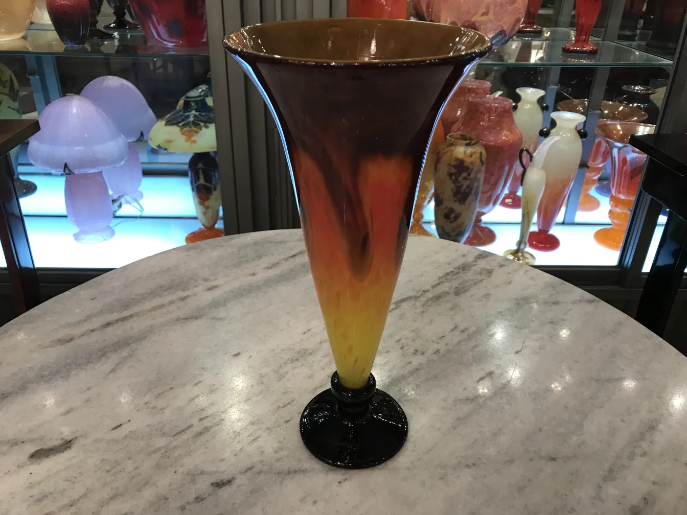Vase made of signed Schneider glass with colorful warm tones, surrounded by antique items.