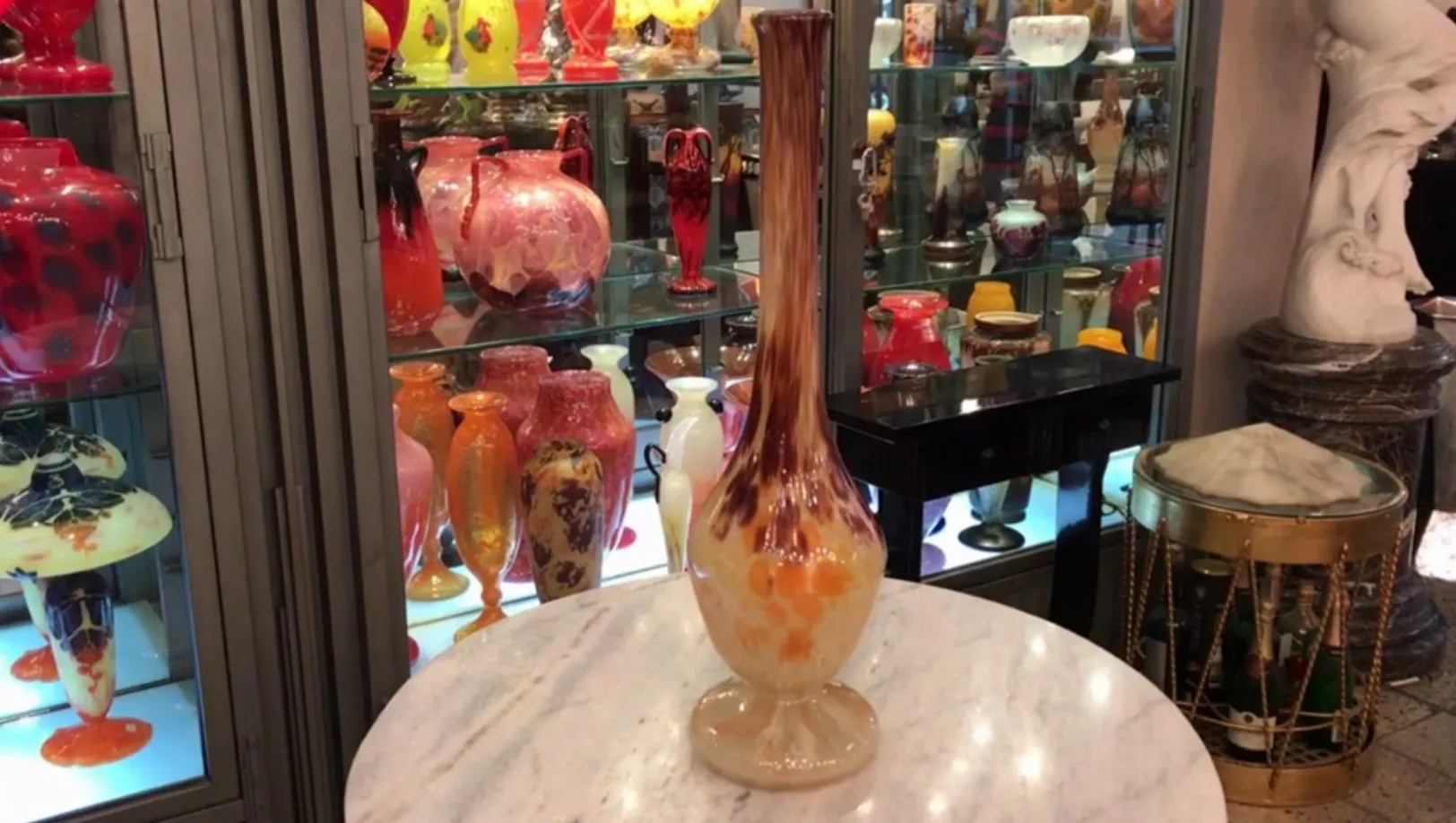 Antique signed glass by Schneider showcasing artistic details with colorful objects in the background.