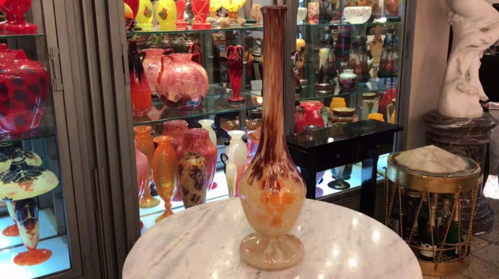 elegantes signiertes glas von schneider vor bunten antiquitäten