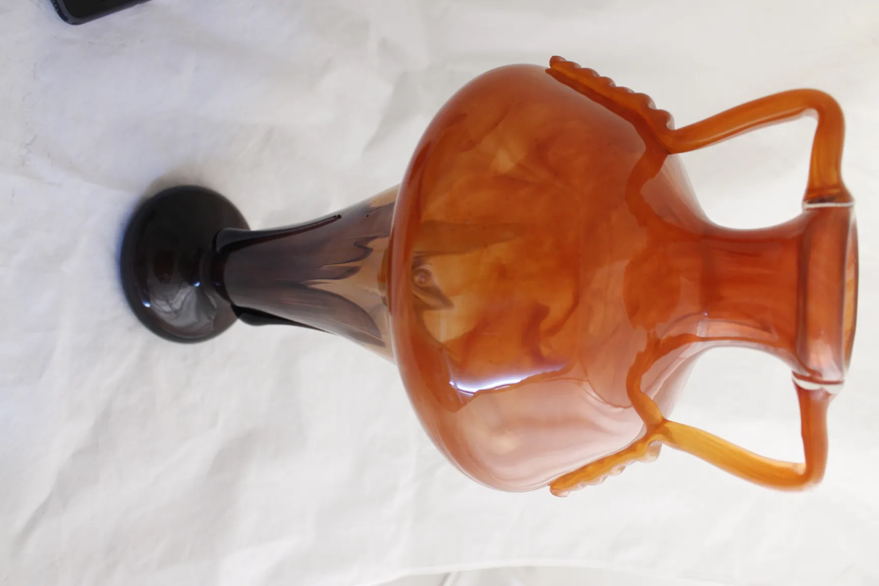 Verre signé par Schneider avec des couleurs chaudes et une forme élégante sur un fond simple.