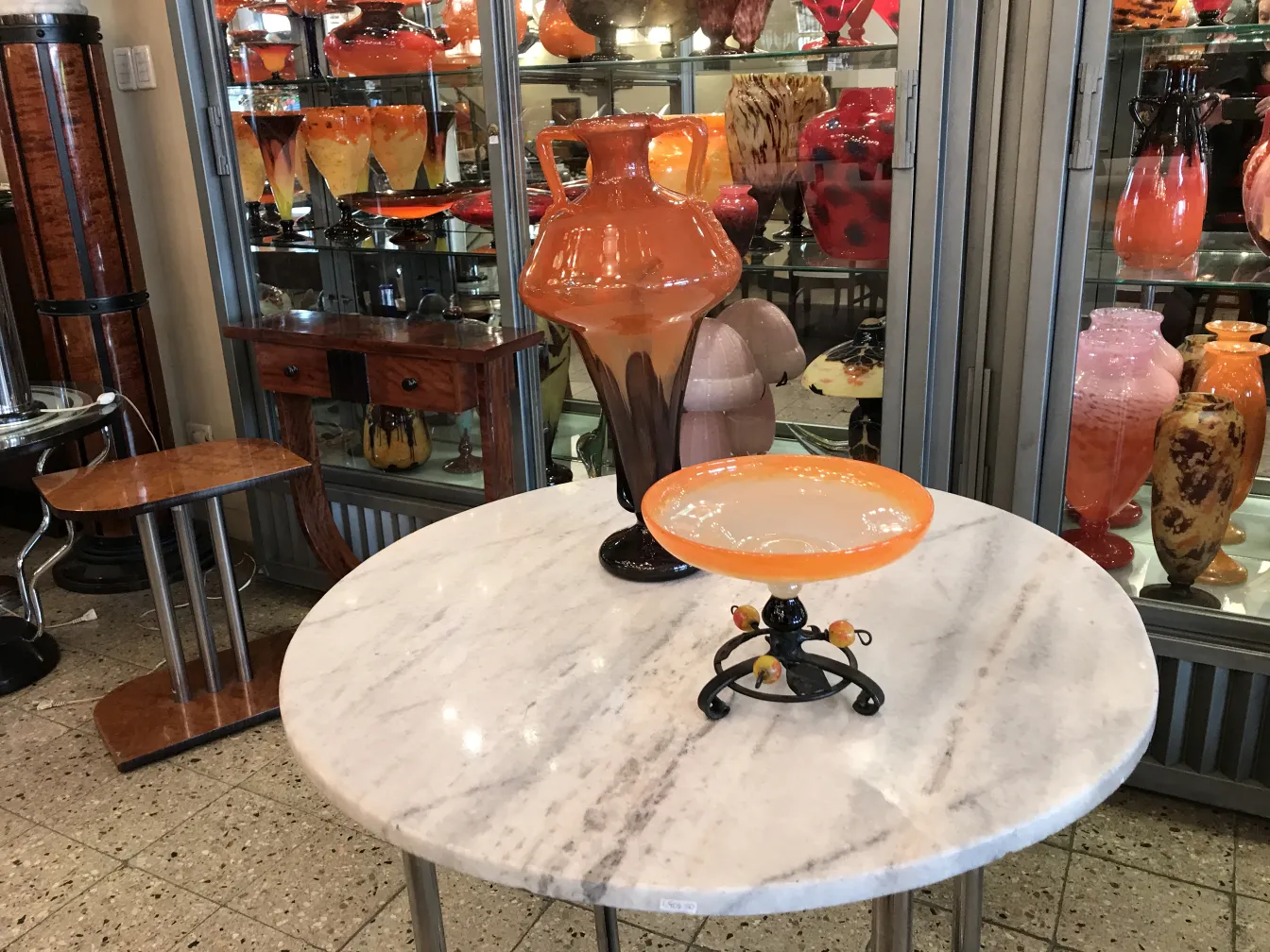 Vetro firmato Schneider esposto in un ambiente di antiquariato con altri oggetti colorati.