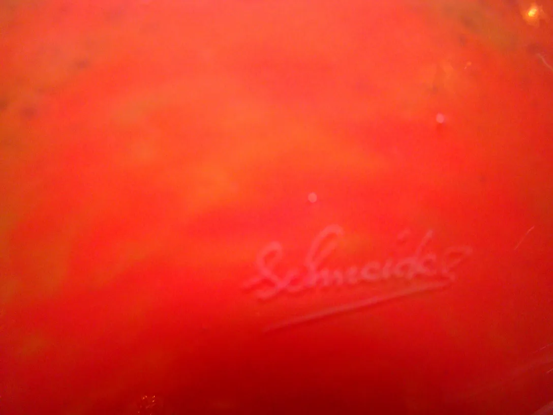 signed glass on a red background with visible signature