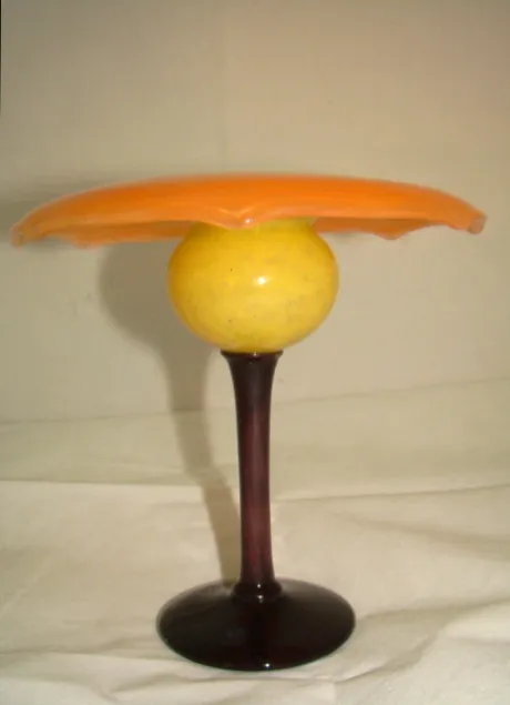 Antikes Glas mit gelber Signatur und schwarzem Fuß.