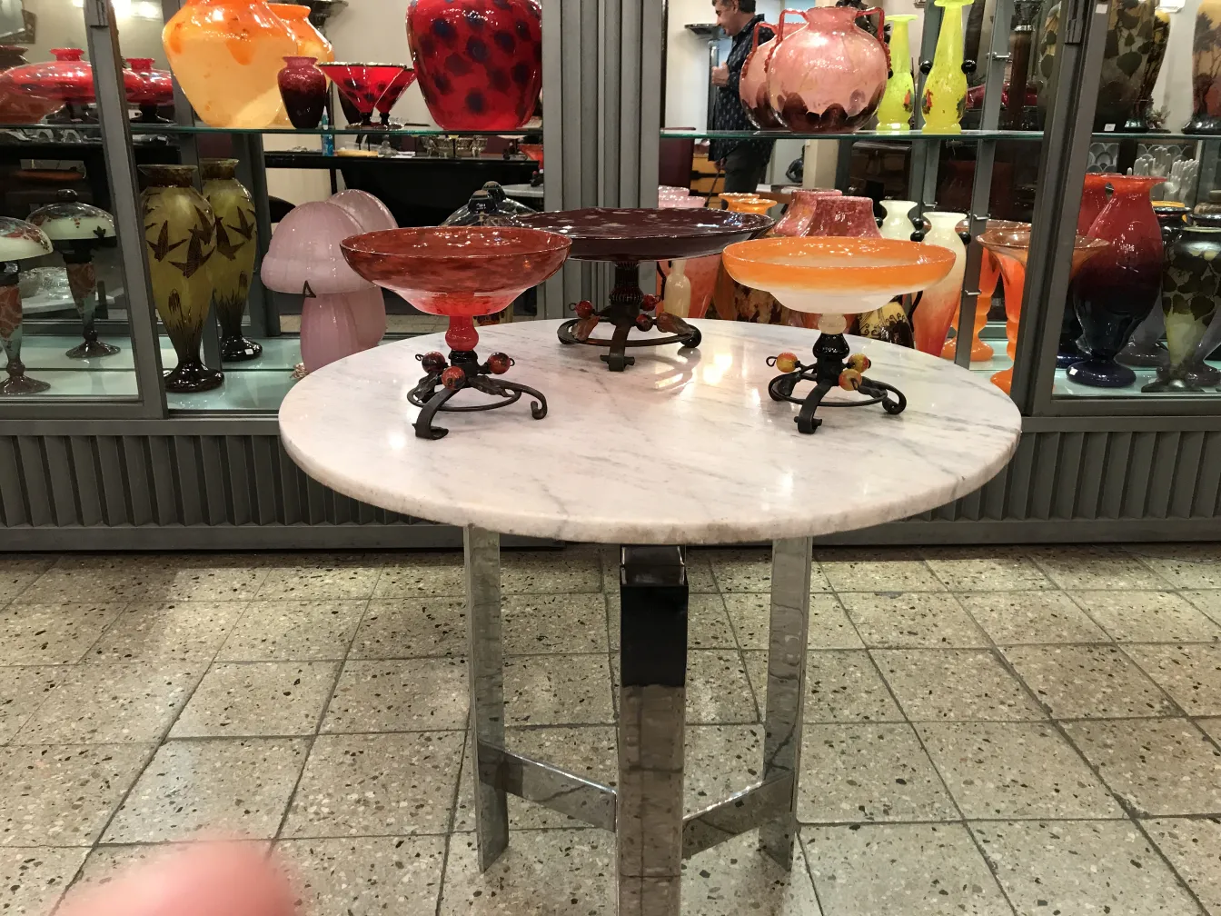 Hermoso vidrio con base decorativa y colores vibrantes en un ambiente de antigüedades.