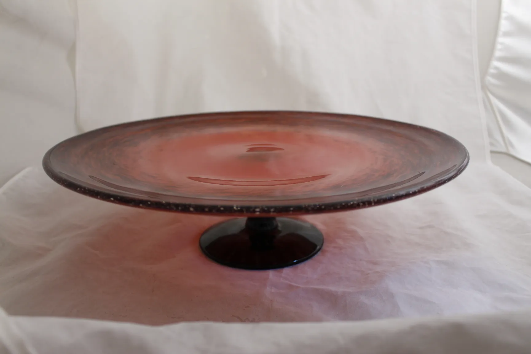 Prato de vidro antigo com pé, cor rosa e design elegante.