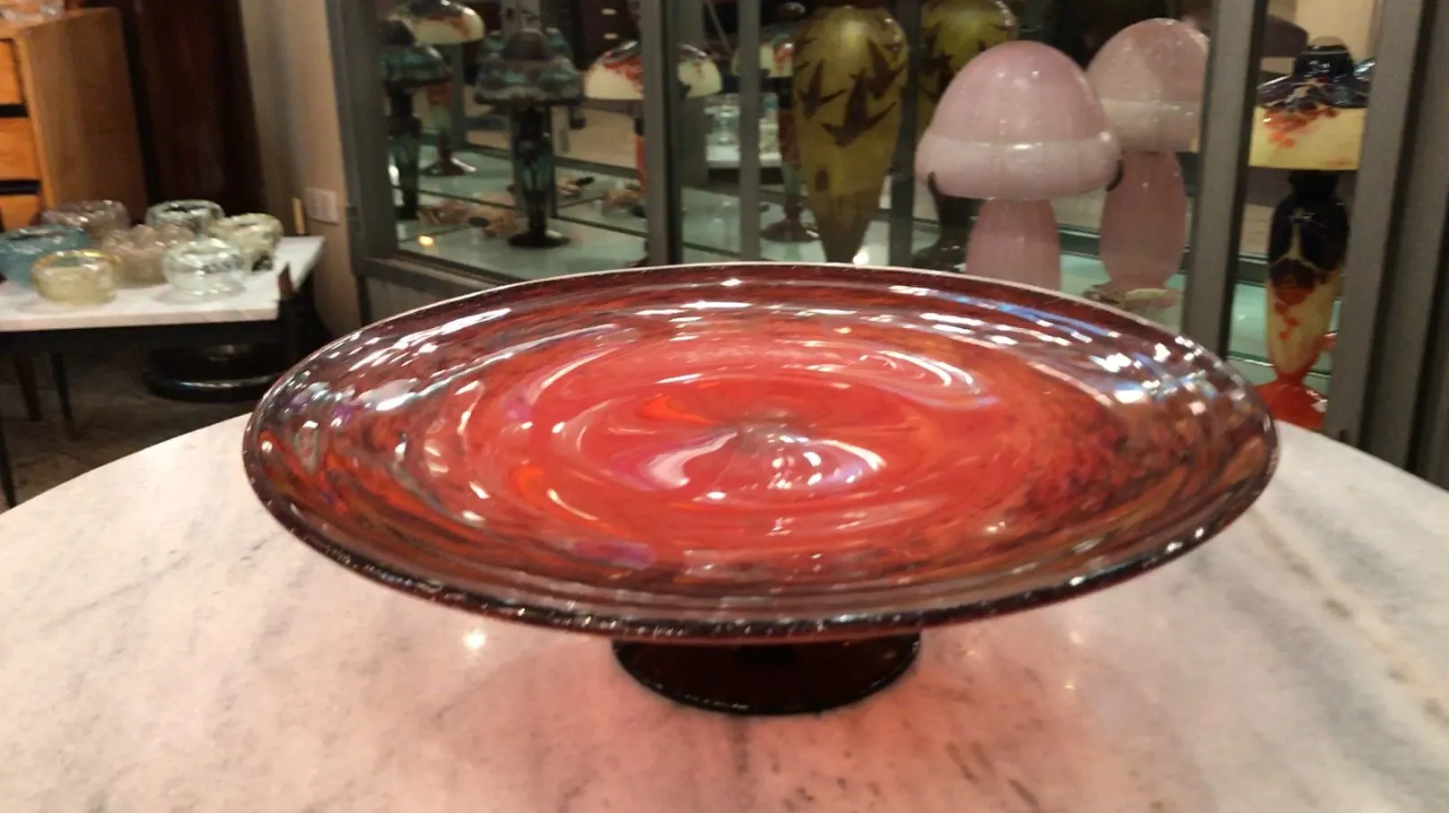 bol en verre signé avec un design tourbillonnant et une base sombre dans une exposition d'antiquités