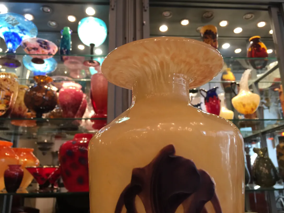 Verre antique signé Schneider avec motif décoratif, entouré de vases colorés.