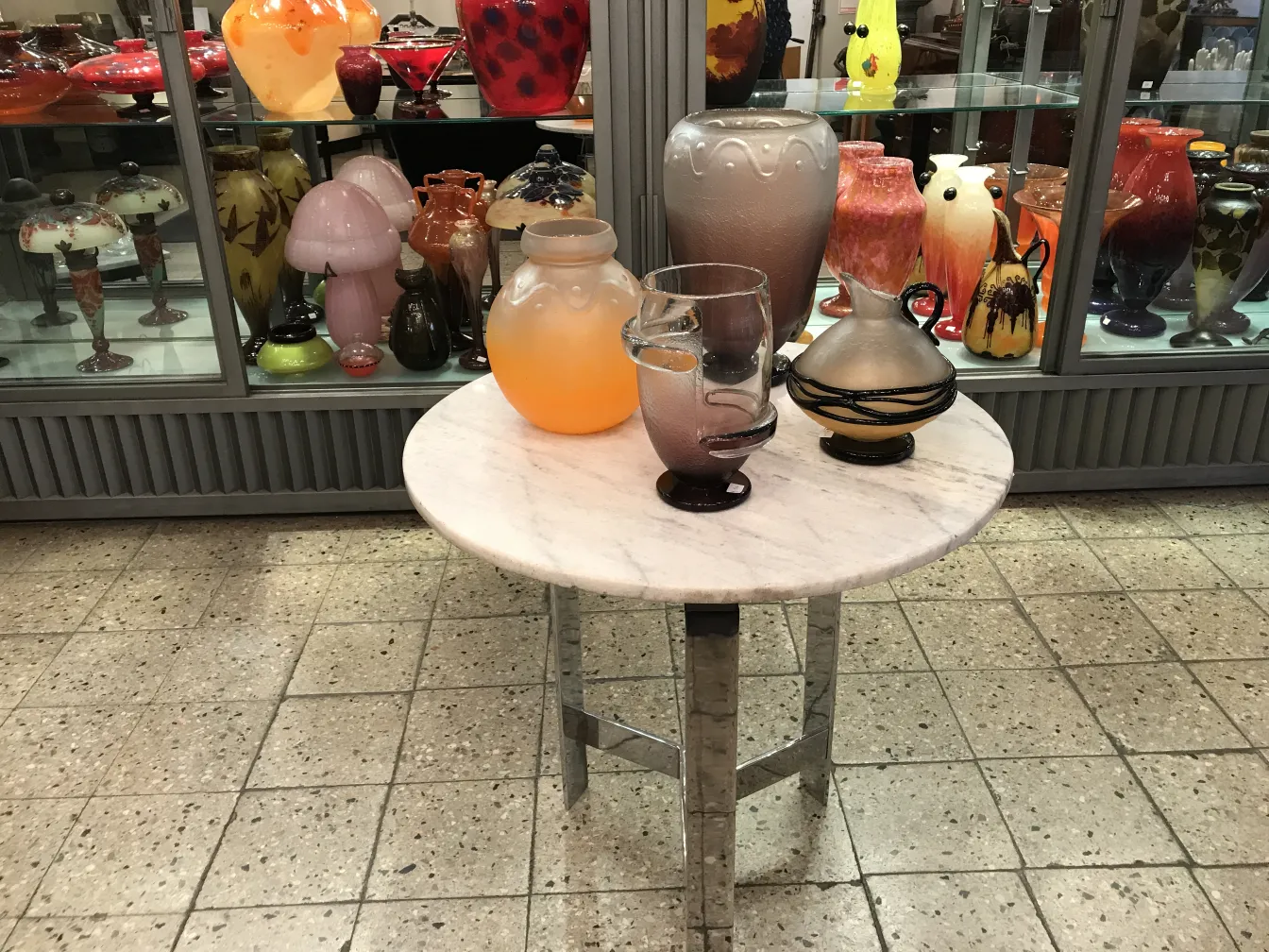 Antique signed glass Schneider, with various colorful vases in the background.