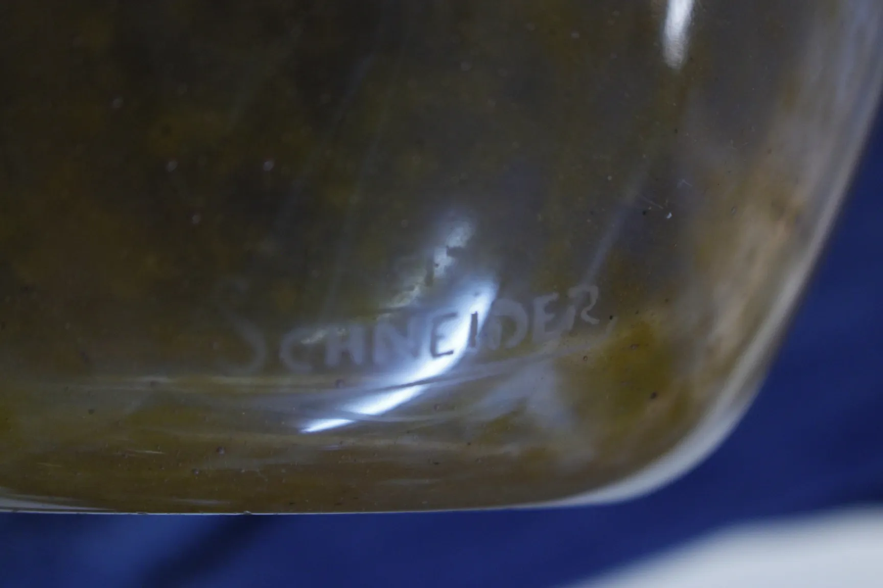 Signed glass with the Schneider mark on a dark background