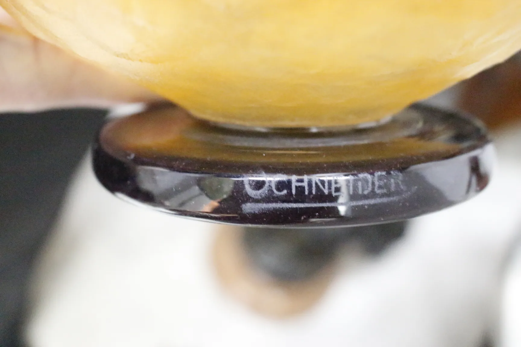 Antikes signiertes Glas von Schneider in einer dunklen Umgebung.