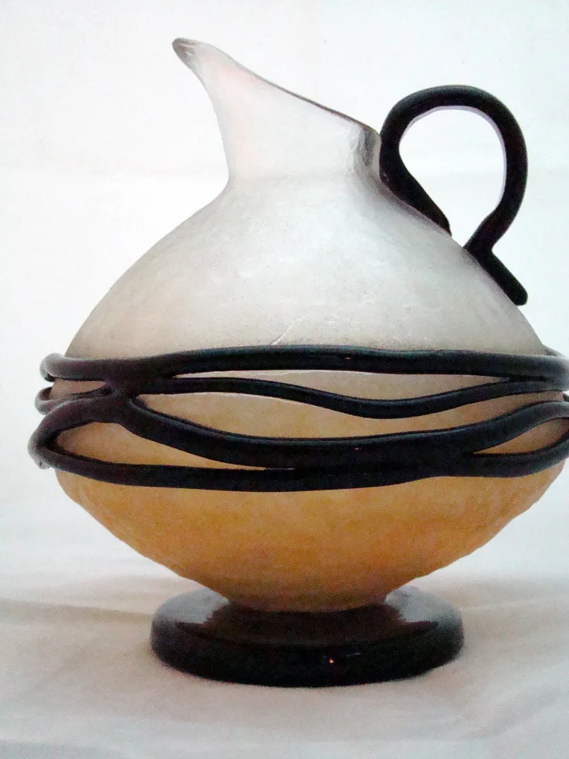 Botijo de vidrio antiguo con diseño único y firma Schneider, ambiente acogedor.