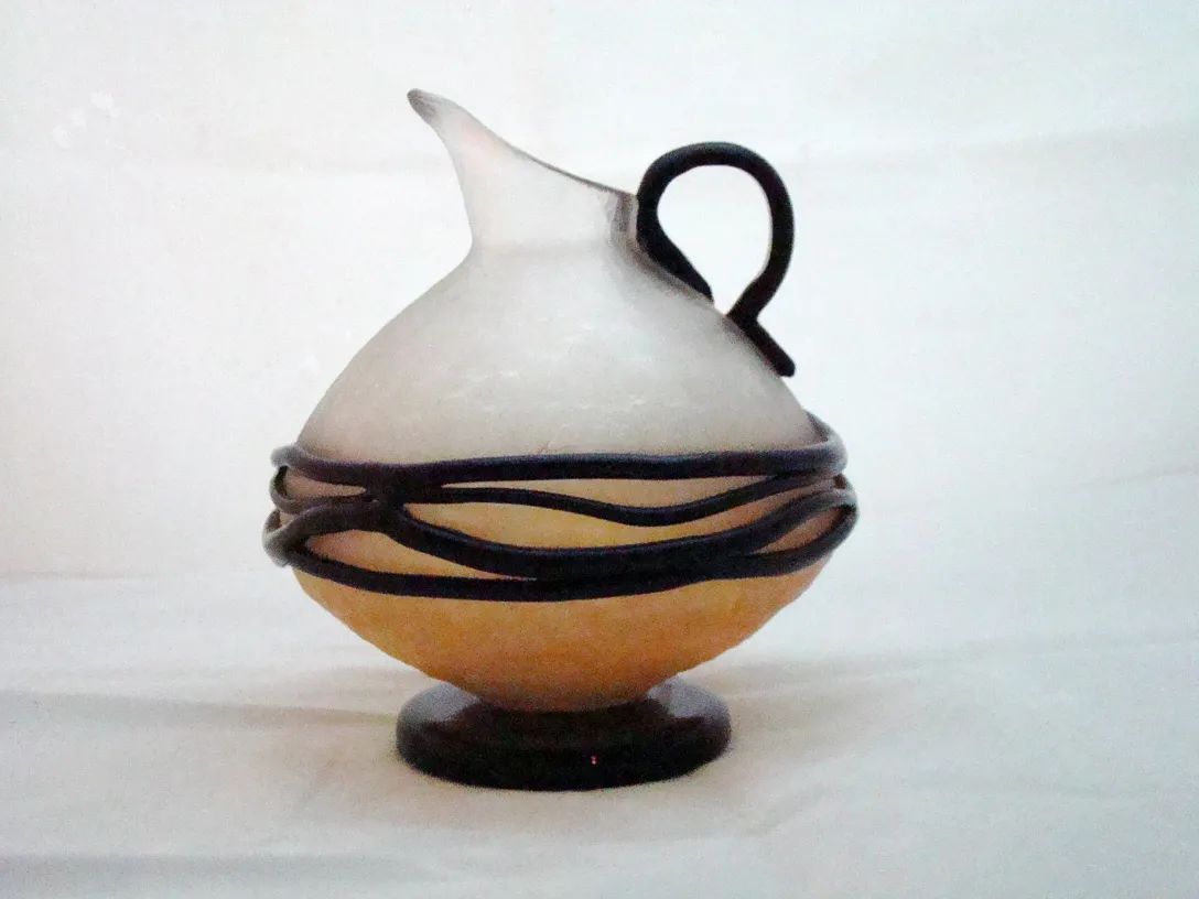 Antique round signed glass with handle, adorned with wire. Neutral background.