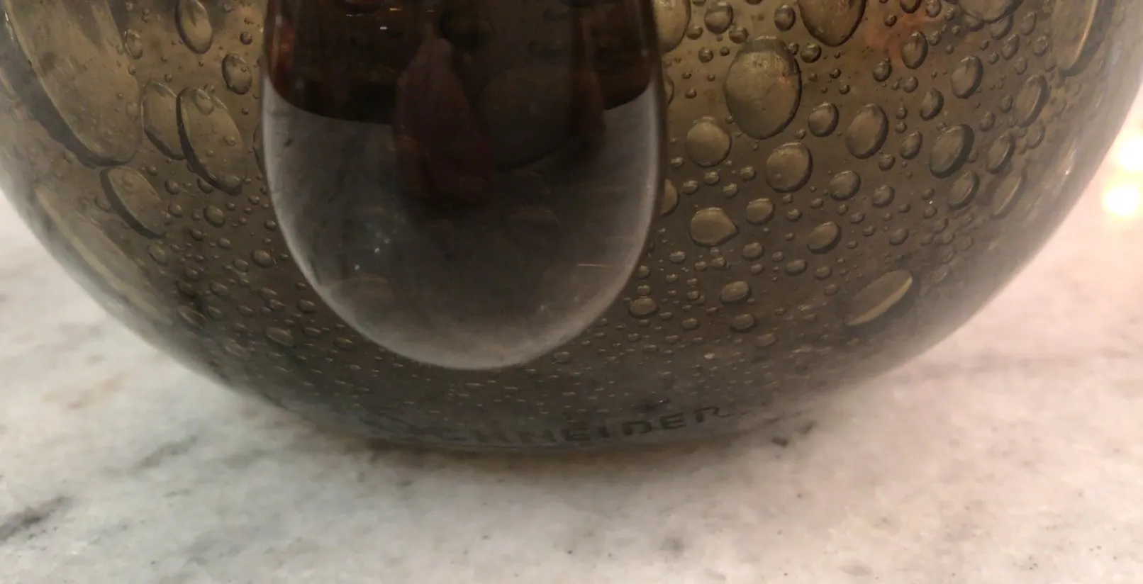 verre signé par schneider avec des gouttes d'eau à la surface