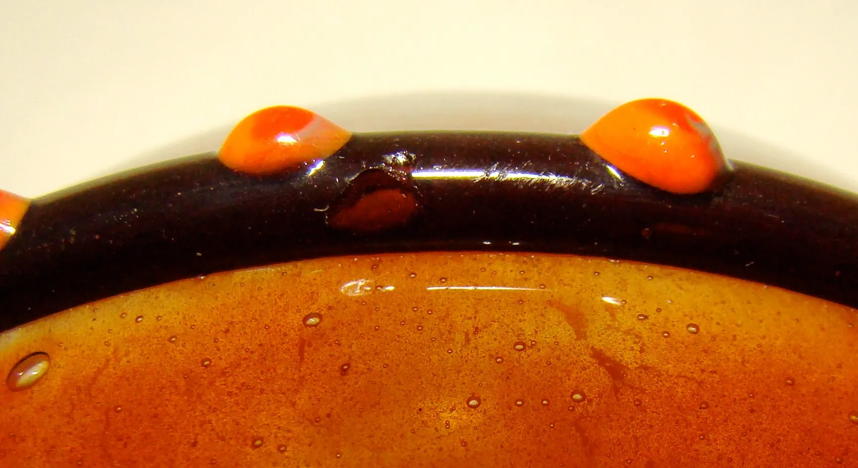 Vidro antigo assinado de Schneider com detalhes em laranja e preto, ambiente clássico.