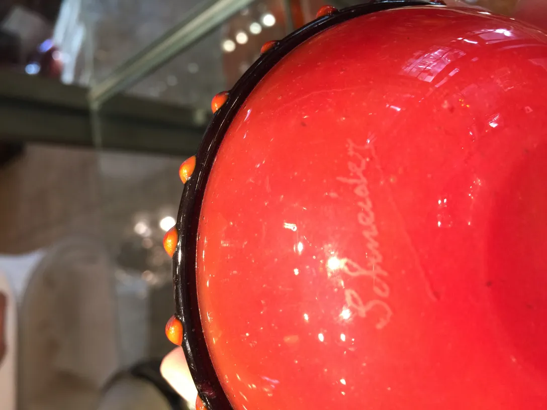 Detail of an antique glass piece with Schneider's signature, featuring vibrant colors.