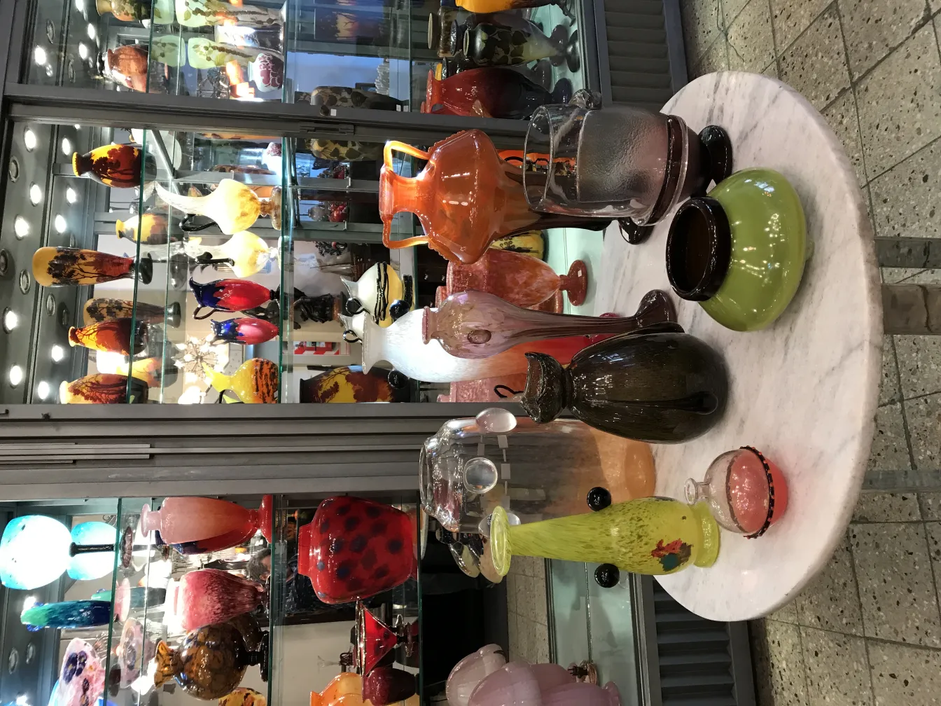 Colección de antigüedades de vidrio con diversos estilos y colores, algunos con decoraciones distintivas.