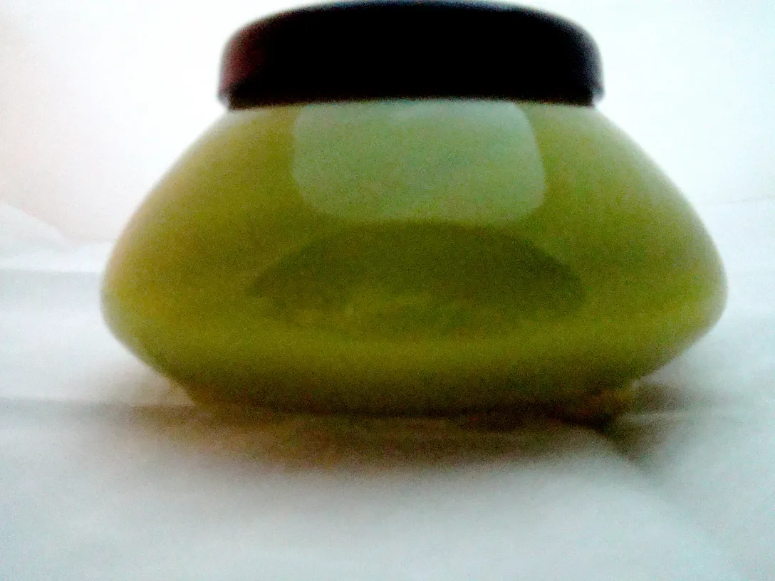 Verre signé ancien de teinte verte avec un couvercle sombre, présentant un design élégant.