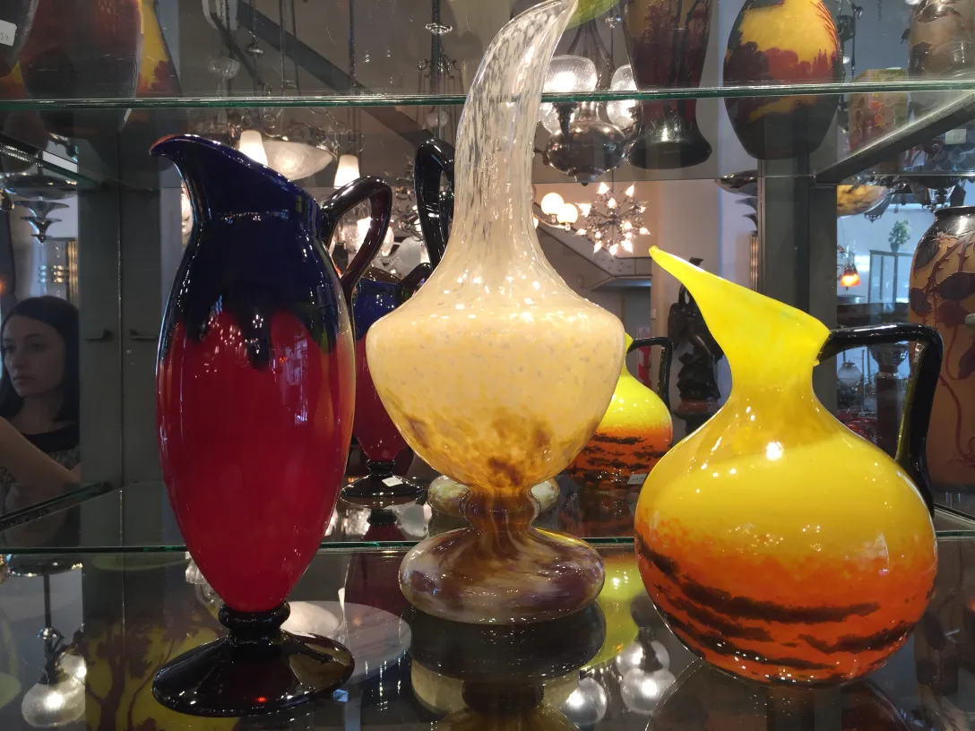 Three antique glass jugs with colorful designs and unique shapes.