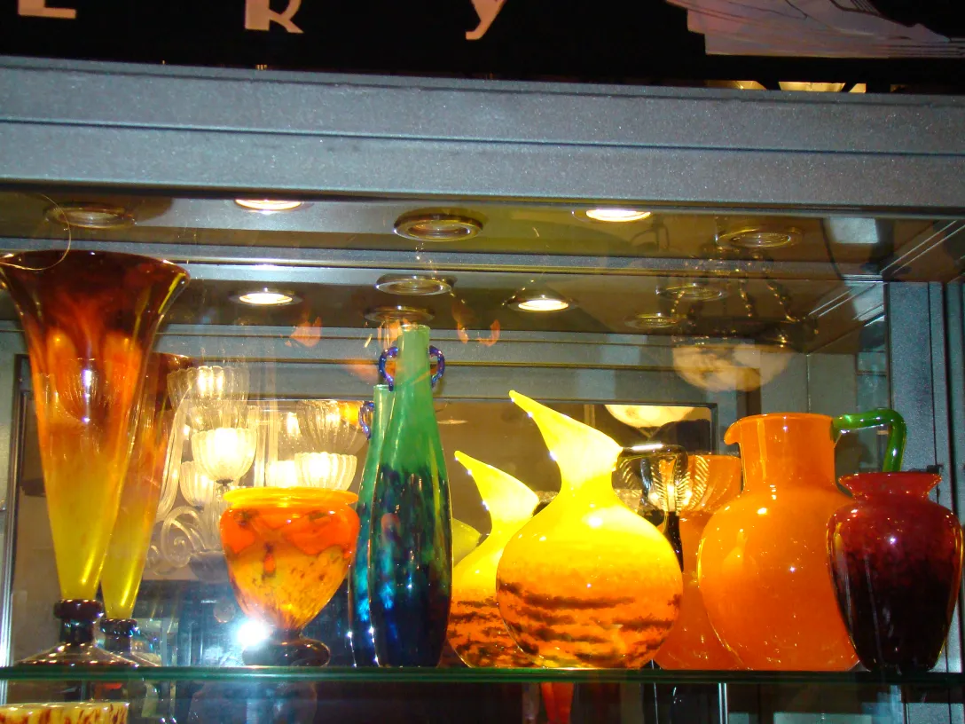 Colorful display of signed glass vases in a showcase.