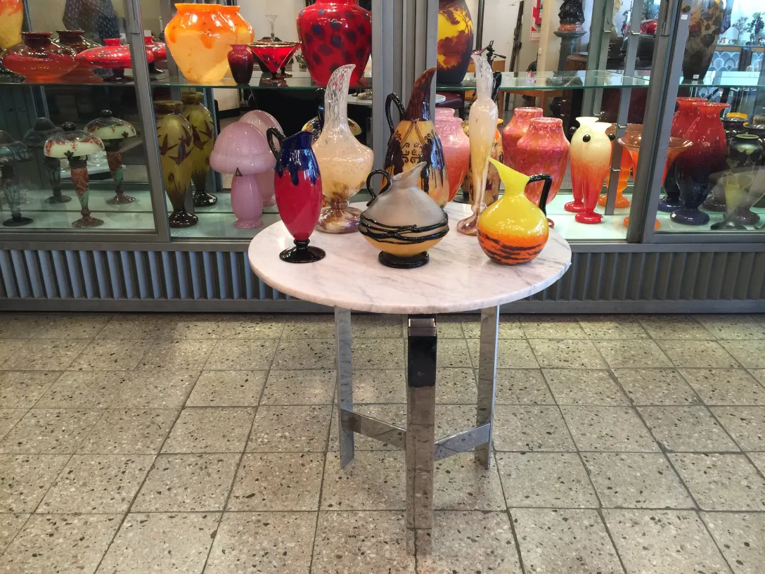 A table with antiques signed glass Schneider and other decorative vases.