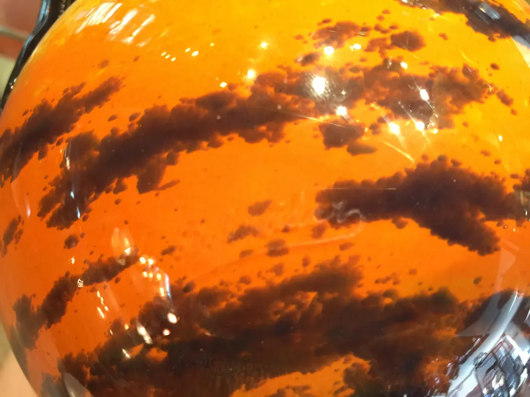 Vidrio antiguo transparente con diseño en tonos naranjas y negros.