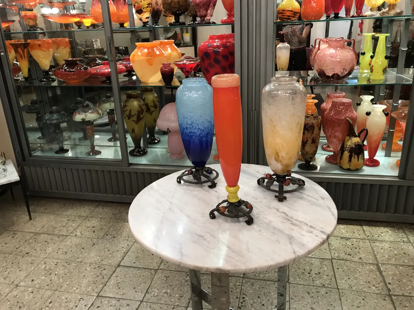 サイン入りグラス（Schneider)（フランス）が古いキャビネットに鮮やかな色で展示されています。