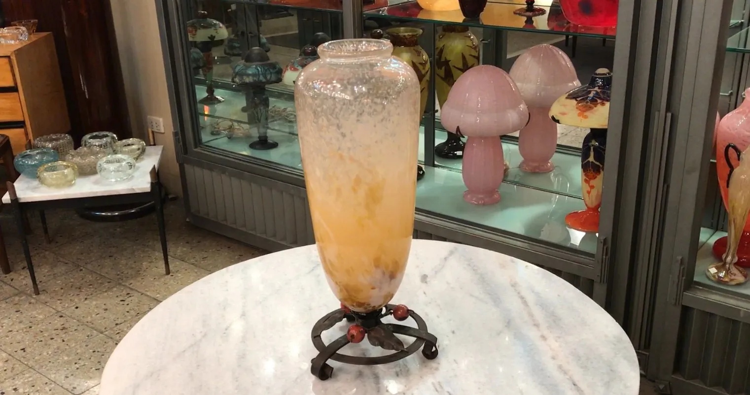 Tall antique glass vase in yellow and white tones with decorative base