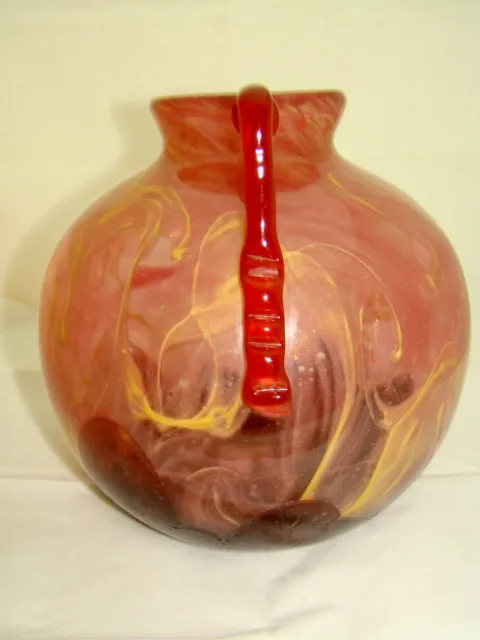 Jarra de vidrio con diseños en tonos rojos y amarillos.