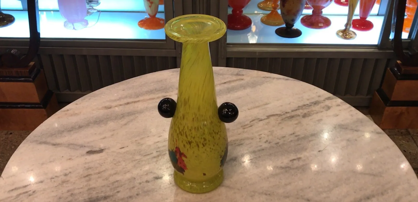 Vidro assinado amarelo com detalhes decorativos e forma elegante em um ambiente de antiguidades